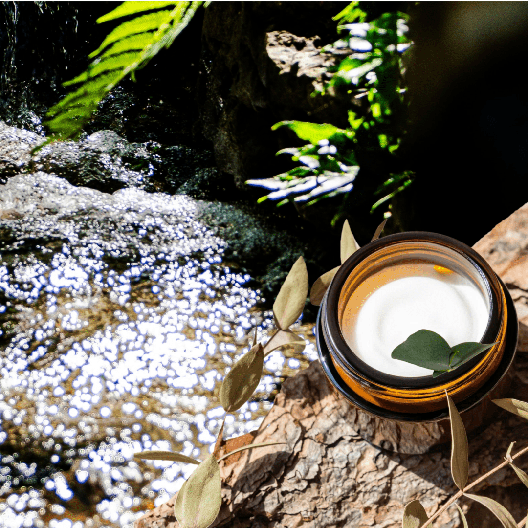 A jar of cream with leaves near a stream.