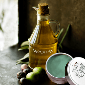 Olive oil bottle, green olives, and balm.