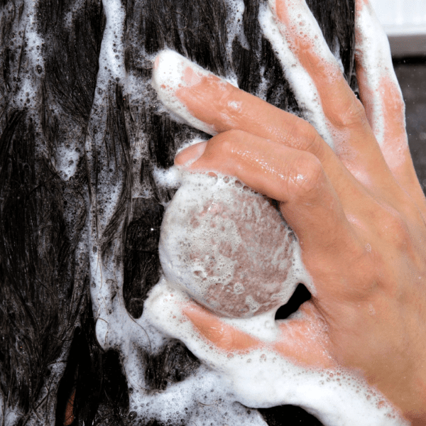 Hand washing dark hair with a shampoo bar.