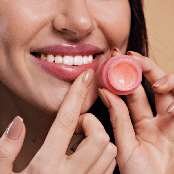 Woman applying lip balm with pink container.