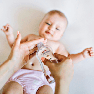 Baby being rubbed with oil by adult hand.