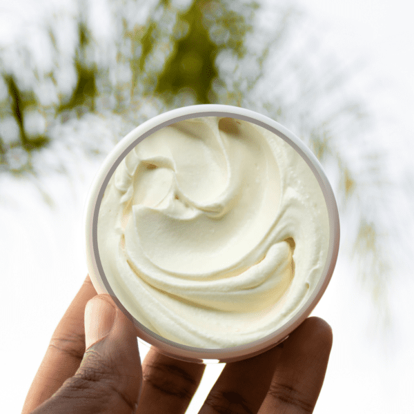 Hand holding a container of white cream.