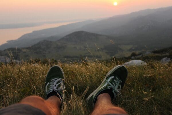 Person in green sneakers resting in grassy hills.